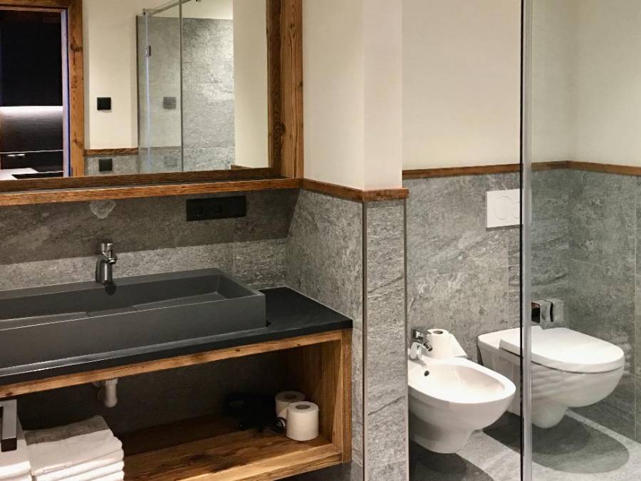 Dunkles Waschbecken mit heller Steinwand, im Hintergrund ein WC - Kiebacher Wahlen