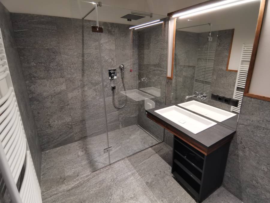 Regendusche im Hintergrund und Waschbecken mit großem Spiegel im Vordergrund - Kiebacher Wahlen