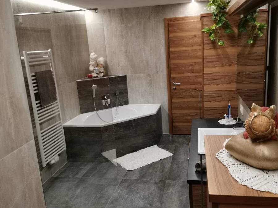 Bad mit Wanne und Dusche mit dunklem Steinboden und heller Steinwand - Kiebacher Wahlen